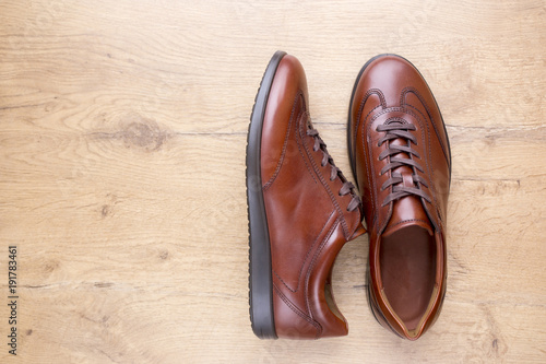 Brown men leather shoes on wooden background © lukaspuchrik