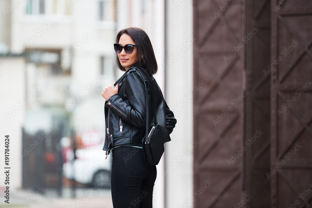 Young fashion woman in black leather jacket walking in city street Young fashion woman in black leather jacket walking in city street