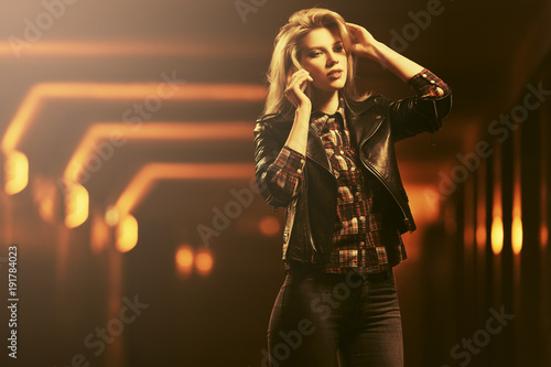 Young fashion blond woman in leather jacket talking on cell phone