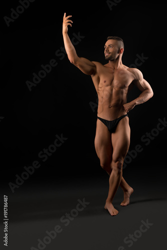Handsome muscular athlete view in dark room