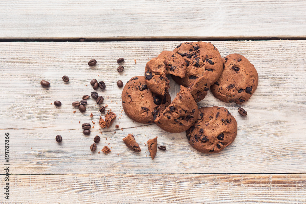 broken chocolate chip cookies with coffee beans on white wooden table broken chocolate chip cookies with coffee beans on white wooden table