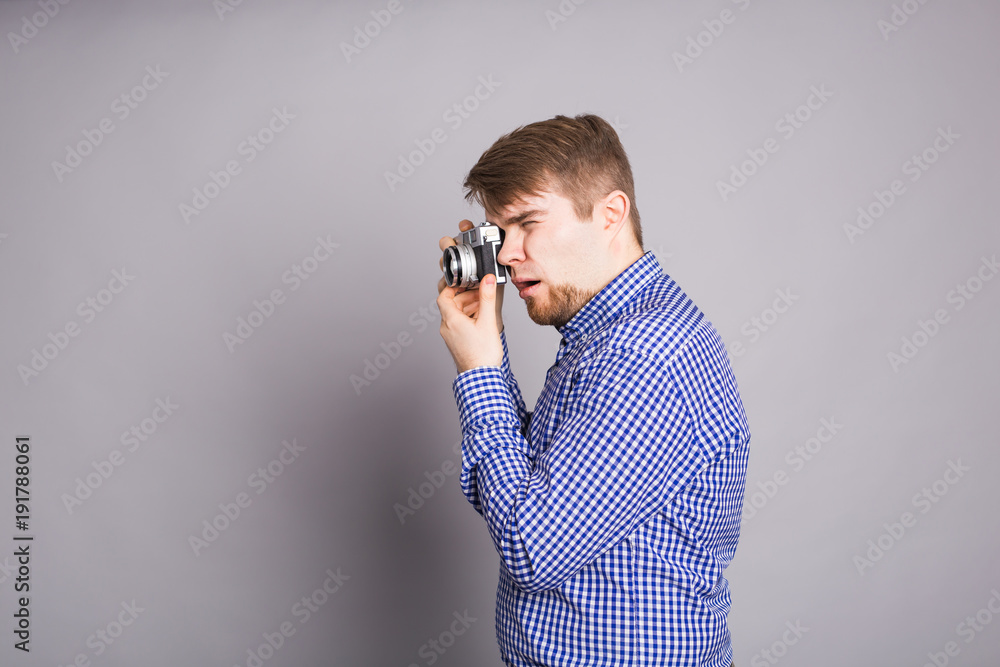Young photographer man holding retro camera on a gray background Young photographer man holding retro camera on a gray background