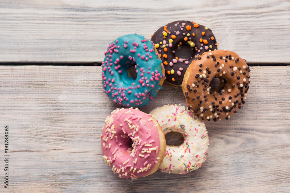 glazed donuts with sprinkles on a white wooden table glazed donuts with sprinkles on a white wooden table