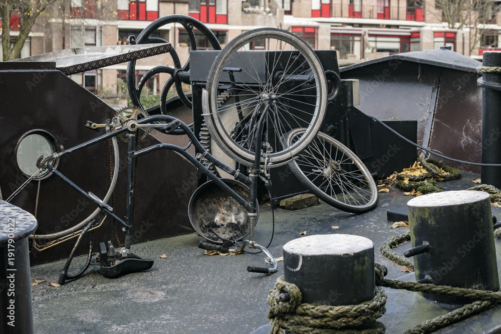 Old half disassembled bicycle on deck of barge in Rotterdam, illustrating traditional boathouse Dutch lifestyle