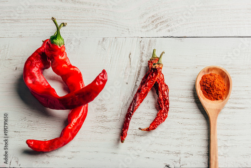 Fresh, dried and ground red chili pepper over colored wooden background.