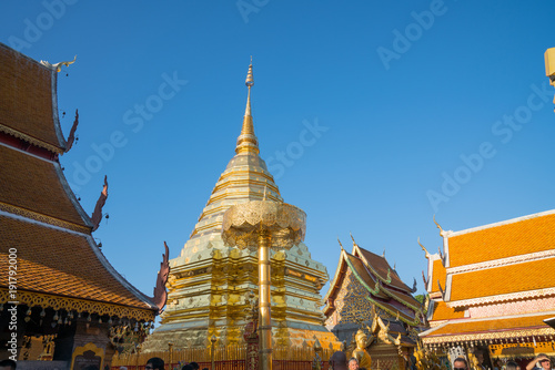 Chedi or stupa between rooftops with Buddhist architectural detail under blue sky
