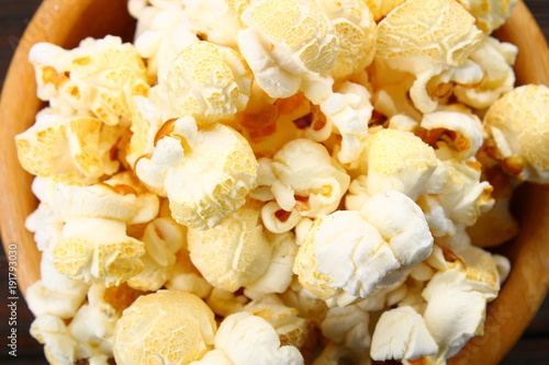 Salted popcorn in a wooden bowl on a wooden table. photo