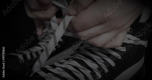 A player in hockey, ties laces on skates, a black background.