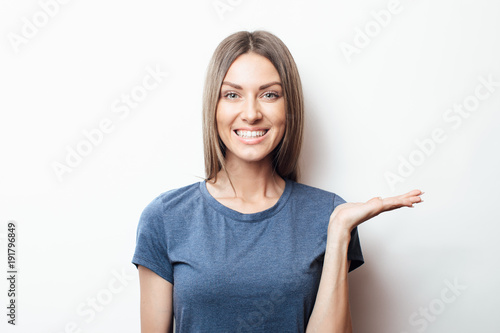 Portrait of young blonde female. showing something interesting at copy space wall for your information or advertising content, winking at the camera and pointing sideways