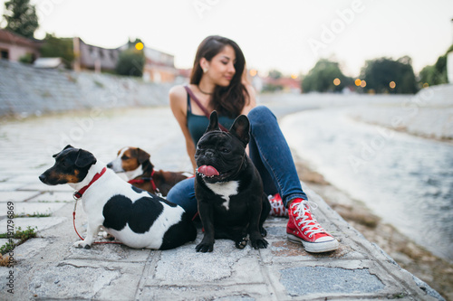 Canvas Print Dog walker with dogs enjoying outdoors next to city river.