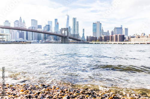 Rocky pebble beach shore water in east river with view of NYC New York City cityscape skyline and bridge, nobody in Brooklyn photo