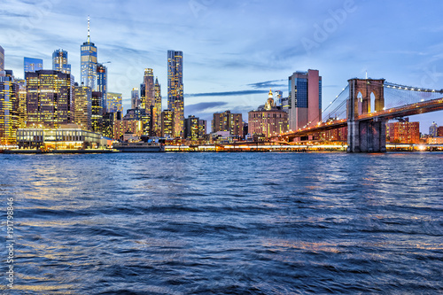 View of NYC New York City downtown lower financial district Brooklyn Bridge skyscrapers, east river, cityscape skyline during evening sunset, dusk, twilight © Kristina Blokhin