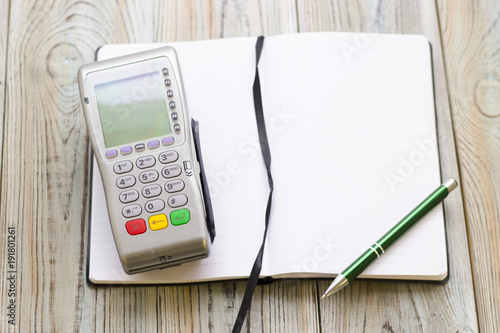 Fotografija Modern technology and people concept - pos terminal and notepad