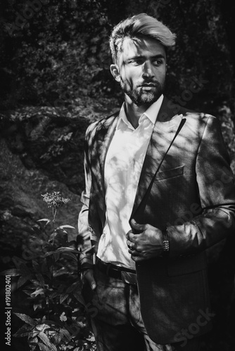 Brutal young man with beard and gray. Stylish Afghan man in jacket costume on the nordic Karelian nature landscape background. Marble Canyon and Dramatic sky in Karelia republic. Karelian forest. BW