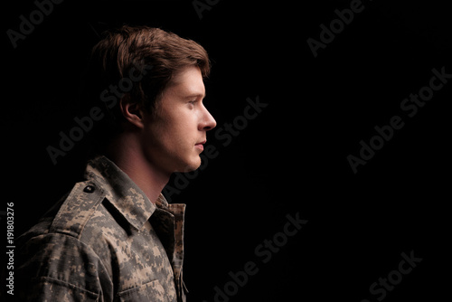 Serene male cadet looking thoughtful and hopeful. He is standing turned in profile. Isolated on background. Copy space in right side