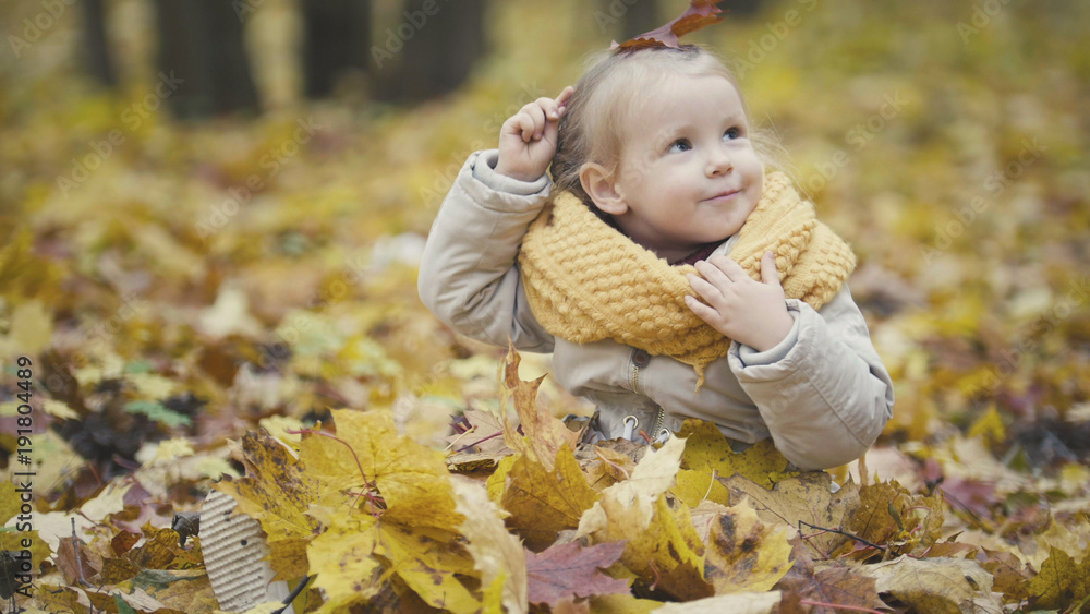 Little daughter plays with yellow leaves in autumn park - the girl is happy and laughing Little daughter plays with yellow leaves in autumn park - the girl is happy and laughing