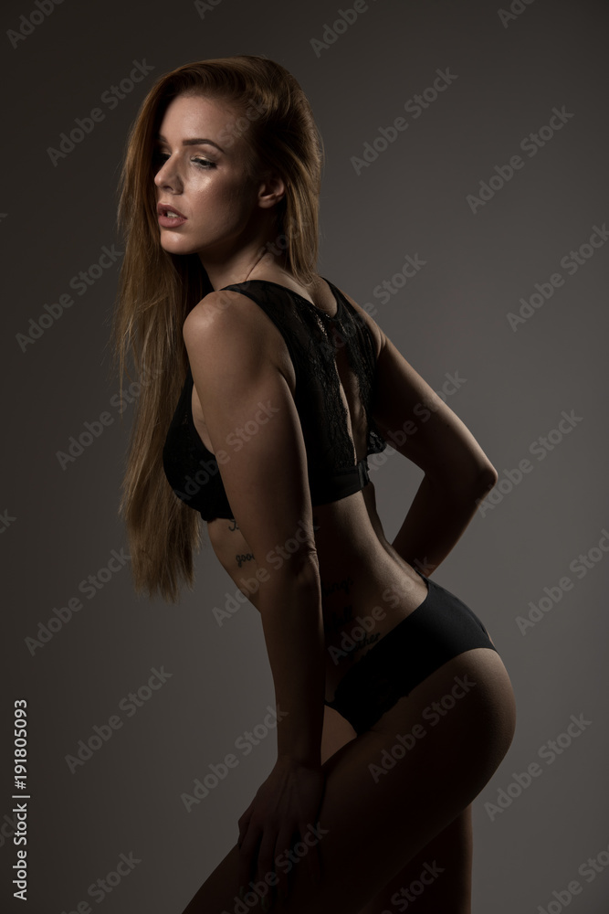 Boudoir photography of a beautiful young woman over dark background