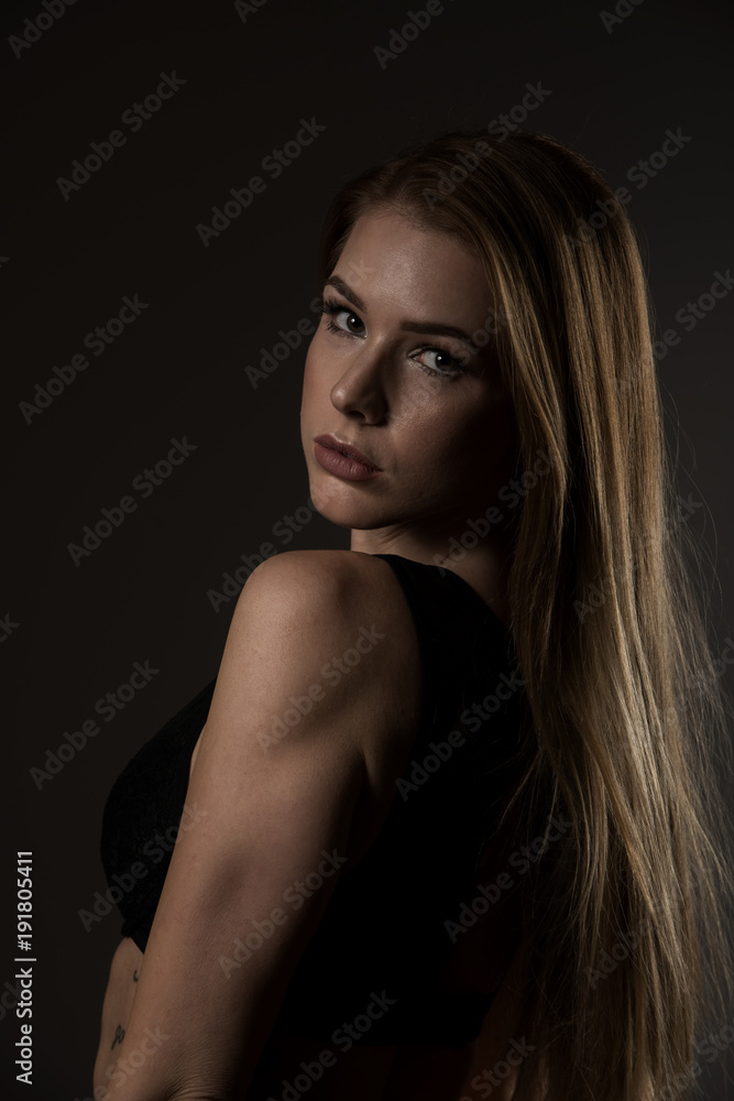 Boudoir photography of a beautiful young woman over dark background