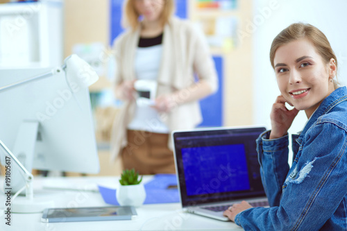 Two young woman sitting near desk with instruments  plan and laptop.