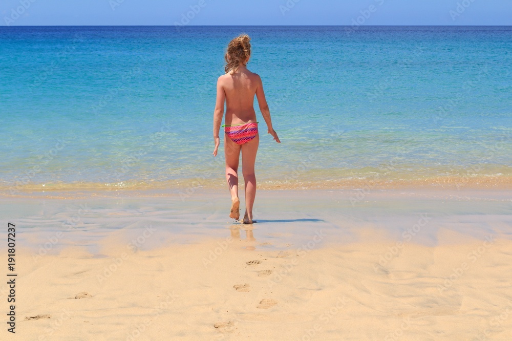 Young girl on the beach are going to the sea, Fuerteventura- Canary Islands