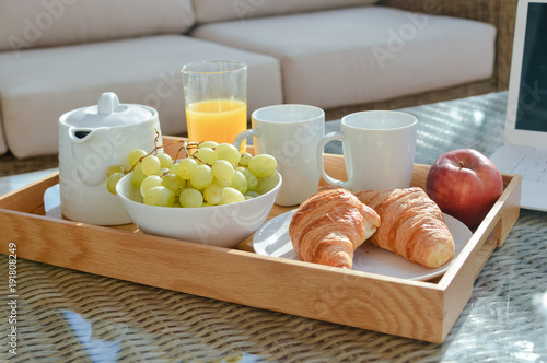 Breakfast on tray served with coffee and fresh flowers on light table background, closeup grocery nutritious balanced diet