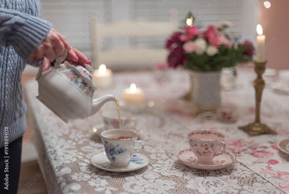 Pouring tea into vintage china teacups in the dining room