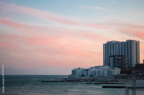 Sunset in ocean. sunset in sea with hight apartment building on background. urban sunset © Alexey Lesik
