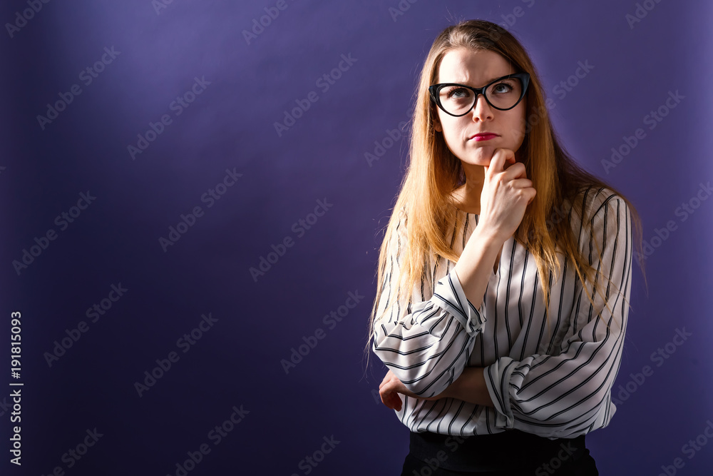 Fototapeta premium Young woman in a thoughtful pose on a solid background