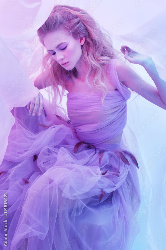 Fashion portrait of young beautiful woman in fluffy violet dress.
