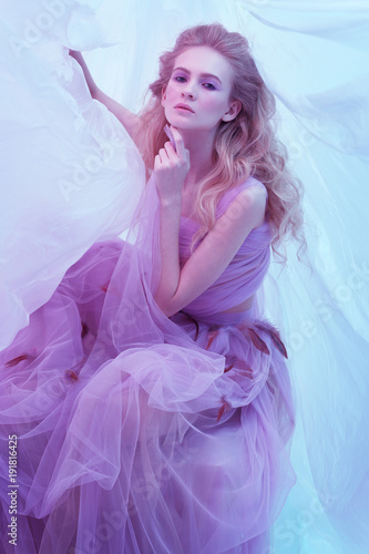 Fashion portrait of young beautiful woman in fluffy violet dress.