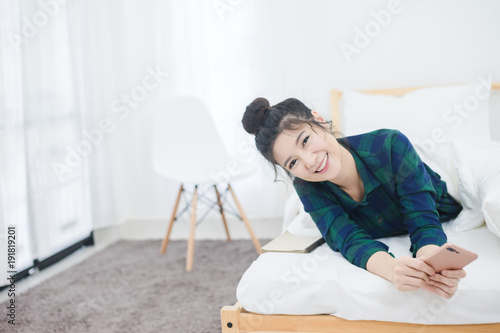 Attractive happy woman use phone on bed and smile