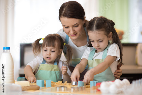 Mother and kids daughters in kitchen making cookies.