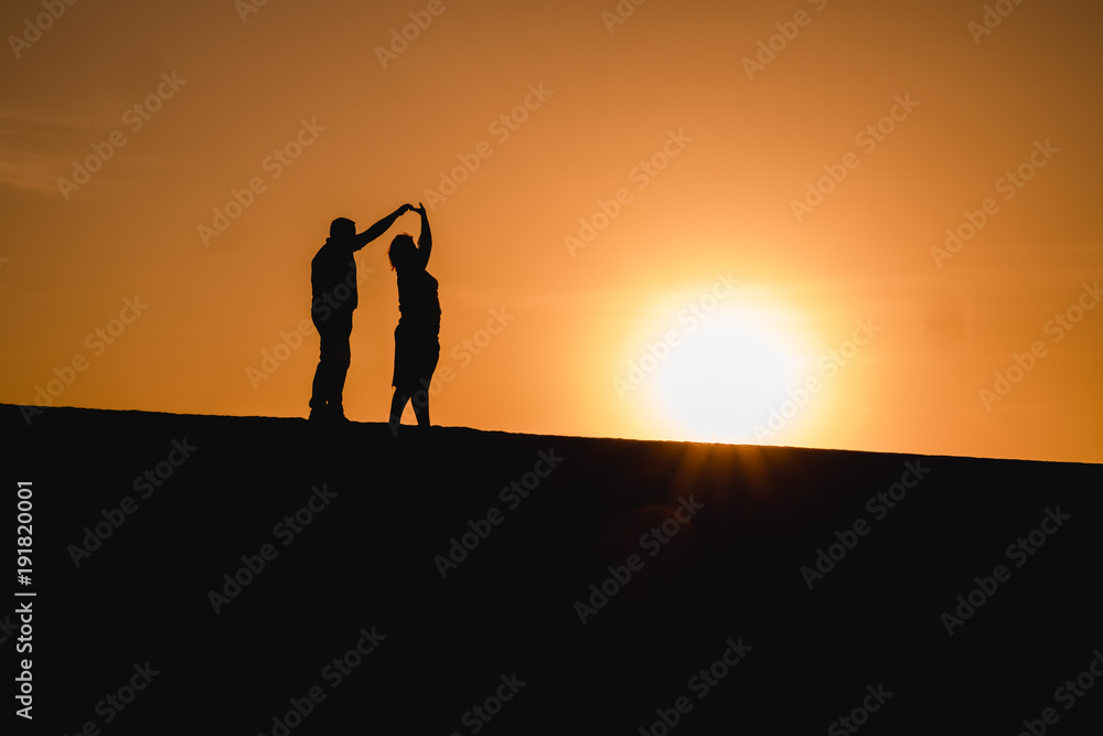 Silhouetten von einem Paar das bei Sonnenuntergang tanzt