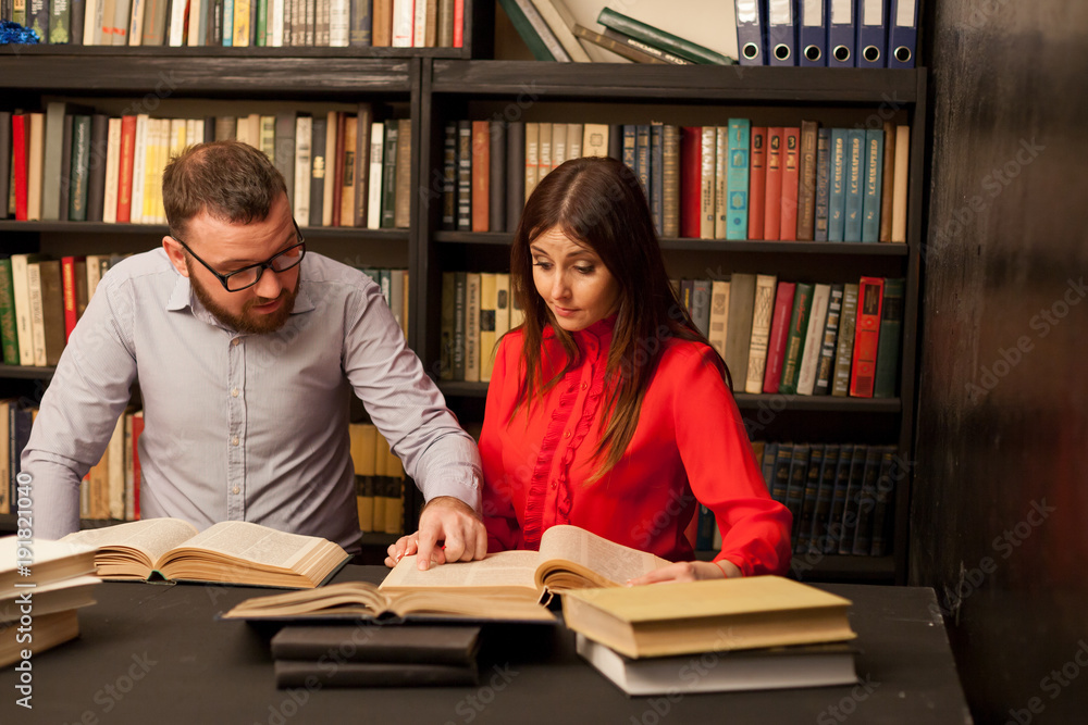 a man and a woman reading a book in the library before the exam a man and a woman reading a book in the library before the exam