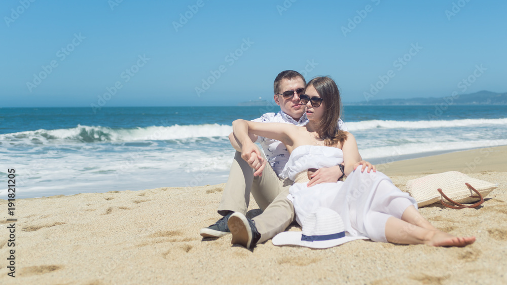Young smiling couple sitting on the beach