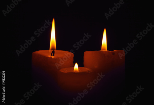Three burning candles in the darkness