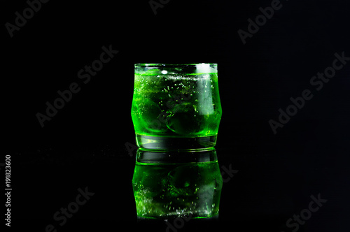 Fresh green italian soda drink with splashing and crushed ice in freeze motion.
