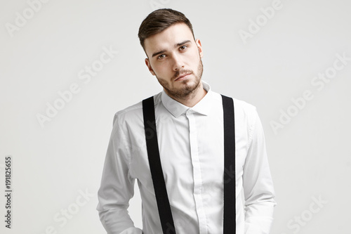 People, business, job, career and employment concept. Studio shot of confident attractive young male chief executive officer with stylish stubble posing isolated at white wall, dressed in formal wear