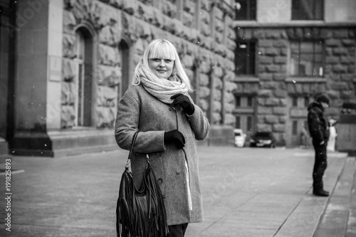 Closeup of beautiful mature woman having a walk in city. Stylish middle age woman wearing coat and scarf at cold weather, outdoor shot. 