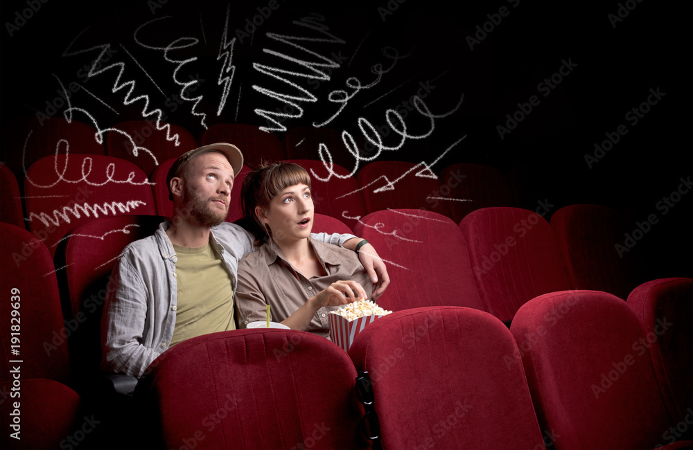 Naklejka premium Cute couple in cinema watching movie