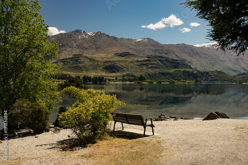 Park bench with mountain reflections on lake photo