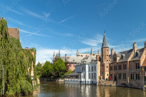 The Rozenhoedkaai canal in Bruges with the belfry in the background. Typical view of Bruges (Brugge), Belgium with red brick houses with triangle shaped roofs and canals.