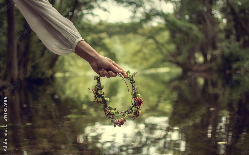 Fototapeta premium Hand of a woman holding a crown of flowers in her hand. Forest area in Frankfurt am Main, Germany. 