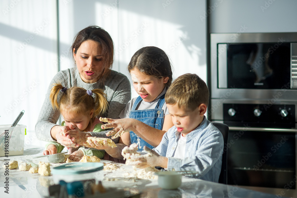 Mother and three children prepare something from the dough.