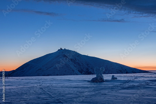The peak of the Snezka Mountain in winter in the Krkonose Mountains. Winter landscape on the ridges in Krkonose, in front of sunrise, beautifully painted in shades of blue color. Travel concept.