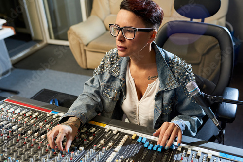 фотографія Thoughtful modern female audio engineer concentrated on mixing sounds while movi