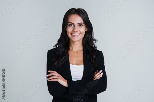 Perfect business lady. Beautiful young businesswoman looking at camera with smile while standing against white background photo