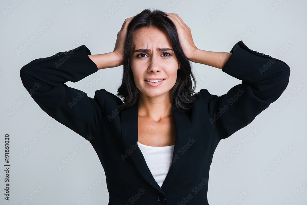 What have I done! Beautiful young businesswoman looking frustrated and keeping head in hands while standing against white background What have I done! Beautiful young businesswoman looking frustrated and keeping head in hands while standing against white background