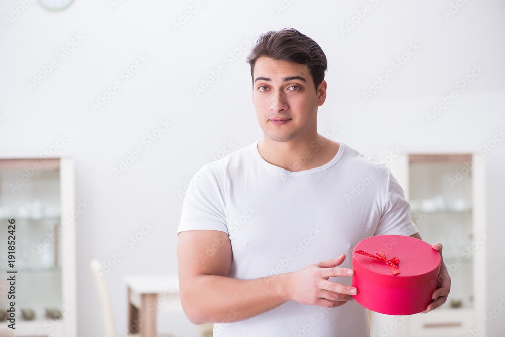 Young man with gift bag at home preparing suprise for wife Young man with gift bag at home preparing suprise for wife