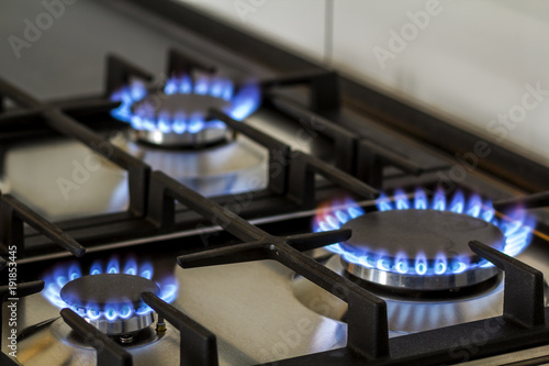Natural gas burning on kitchen gas stove in the dark. Panel from steel with a gas ring burner on a black background, close-up shooting